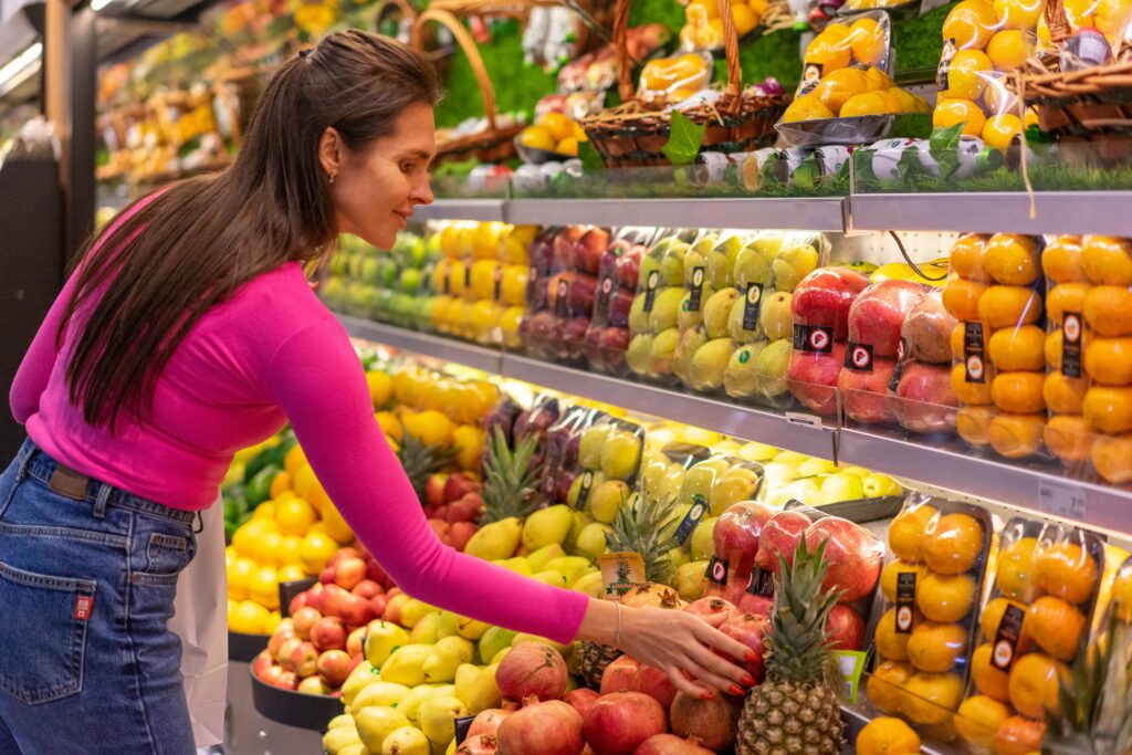 Woman selecting fresh fruits from a supermarket rack